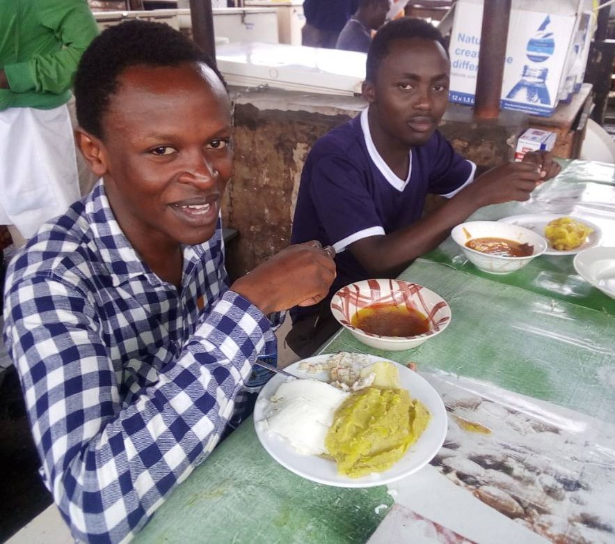 Kenyan hopefuls Milton Kihara (checked shirt) and James Kabui enjoying some Ugandan food.