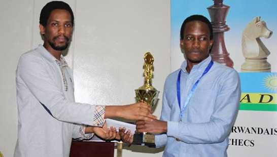 President of Rwanda Chess Federation Kevin Gwanza (left) presents the winning trophy to winner FM Patrick Kawuma of Uganda.