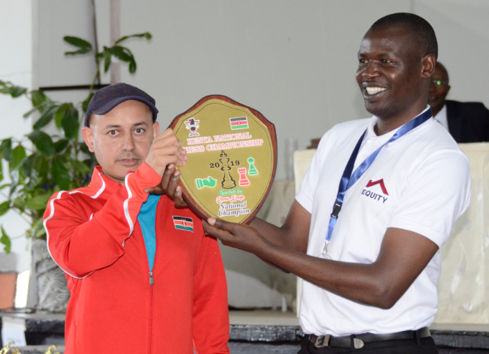 2019 Kenya National Champion Mehul Gohil (left) receives his shield from Chess Kenya President Benard Wanjala. Photo credit Kim Bhari.