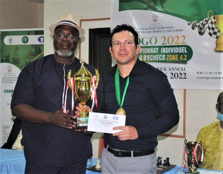 The National Sports Director Kodjo Etse (left) presents IM Mariano Ortega with his trophy for winning the 2022 Zone 4.2 Chess Championship.
