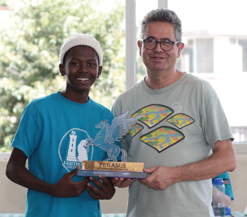 Willy Simons the Chairman of Nairobi Chess Club presents Jamie Obora with the winners trophy. Photo credit Allan Rongoey.