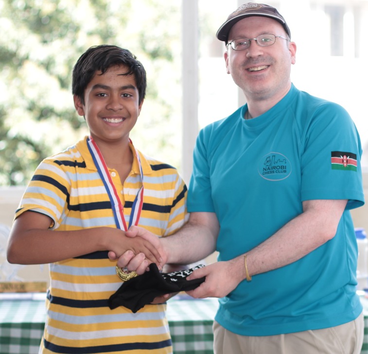 Sarthak Patnaik receives his prize from Warren Pollock the Secretary of Nairobi Chess Club. Photo credit Allan Rongoey.