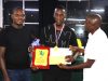 FM Haruna Nsubuga (centre) receiving his prize for winning the 2024 Zabasajja Memorial Chess Tournament.