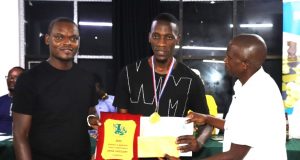 FM Haruna Nsubuga (centre) receiving his prize for winning the 2024 Zabasajja Memorial Chess Tournament.