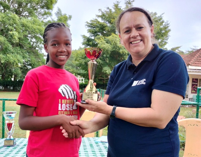 Shirlyn Gathoni Onyango (left) receives her trophy from Bronwynne van Rijn the Academic Administrative Assistant of The School of Nations.